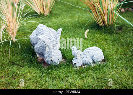Toy Grey Brick Rabbit Family Eating in the Lawn, Eating the grass in Good Weather. Stock Photo