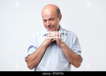 Cunning tricky mature man thinking looking with hand together over gray background. Concept of unfair game Stock Photo