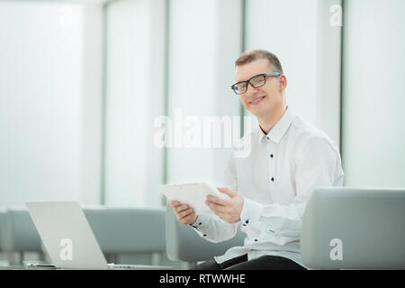 young employee with a digital tablet sitting in a bright office Stock Photo
