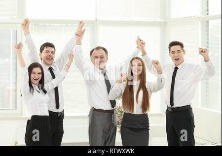 group of happy young people in formal wear celebrating, gesturing, keeping arms raised Stock Photo