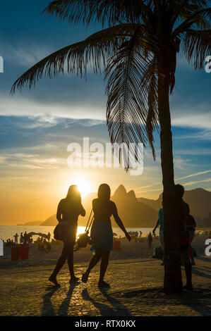 Golden scenic sunset view of Ipanema Beach from the Arpoador overlook with palm tree silhouette in Rio de Janeiro, Brazil Stock Photo