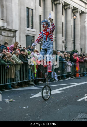 London, United Kingdom - January 1, 2007: Man in clown costume rides unicycle, and waves to cheering crowd, during New Year's Day Parade.