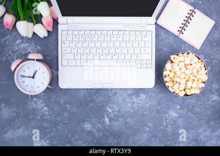 Notebook Notepad Alarm Clock Bouquet of tulips Popcorn in a bowl on the female desktop Stock Photo