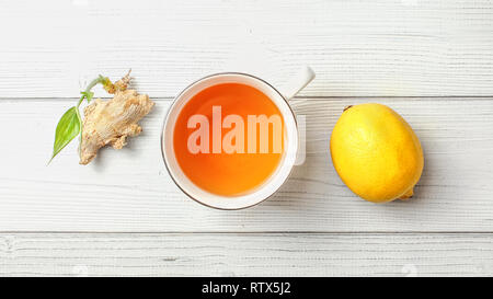 Table top view, cup of freshly brewed tea, lemon, and dry ginger root with green sprout, next to it. Stock Photo