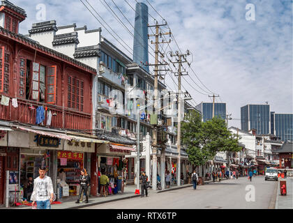 A street view in Old Shanghai. Laundry hangs out to dry on the window rails of the old houses, behind which the Shanghai tower rises up. China. Stock Photo