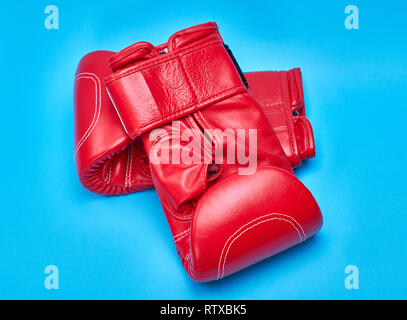 pair of red leather boxing gloves on a blue background Stock Photo