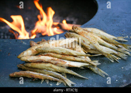 Traditional fried fish being cooked at the spring market in Vilnius with fire, Lithuania. Variety tasty street food on Easter fair Stock Photo