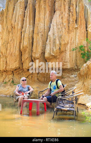 NAM TIEN, VIETNAM - FEBRUARY 15, 2018: Tourist sit on chairs in a river called Fairy Stream in Nam Tien, Vietnam on February 15, 2018 Stock Photo