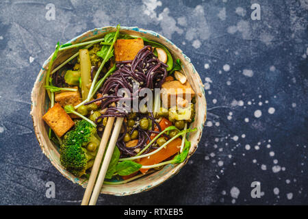 Asian vegan stir fry with tofu, rice noodles and vegetables, top view, copy space. Stock Photo