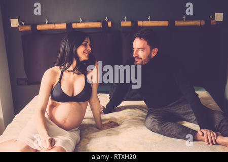 happy caucasian couple of people with pregnant woman and new dad laying on the bed at home and enjoy the future and the situation to make better life  Stock Photo