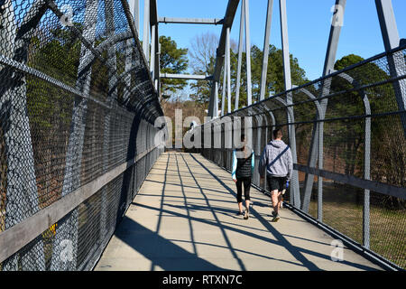 A couple crosses the Reedy Creek Trail pedestrian bridge over the 440 interstate in Raleigh North Carolina. Stock Photo