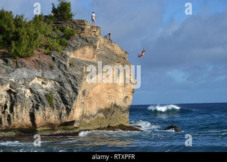 Man jumps from the top of a rock in Shipwreck Beach, Poipu, Kauai, Hawaii, USA Stock Photo