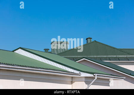 green rooftops of houses with new rain gutters on clear blue sky background Stock Photo