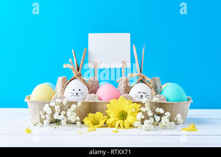 Easter colored eggs in paper tray with decorationd on blue background Stock Photo