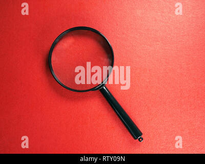 Plastic magnifying glass on a red background, close-up Stock Photo