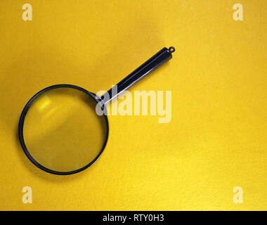 Plastic magnifying glass on a yellow background, close-up Stock Photo