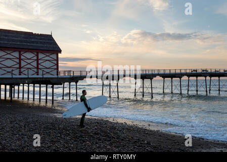Surfer looking out to sea beside Saltburn pier on the coast of North Yorkshire, England. Stock Photo
