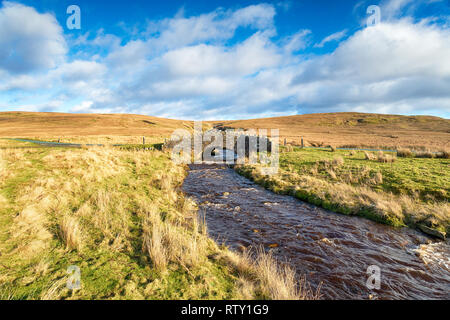 A stone bridge over the Arkle Beck on the Pennine Way as it crosses Tan Hill in the Yorkshire Dales Stock Photo