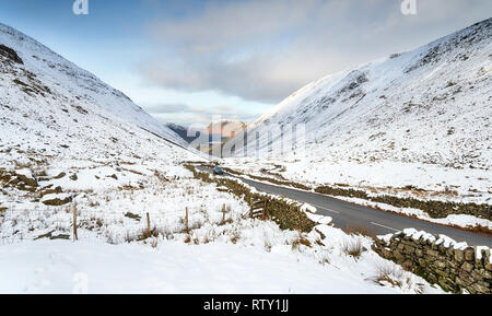 A snowy Kirkstone Pass, the highest mountain pass in the Lake District national park in Cumbria, looking out to Brotherswater in the far distance Stock Photo