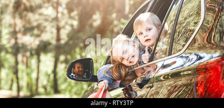 Blond caucasian children, boy and girl looking out the window while traveling with their parents in a car . Safe trip, journey driving concept. Stock Photo
