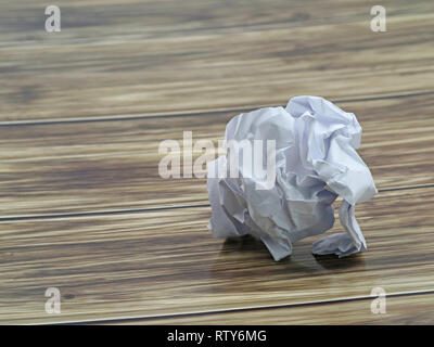 crumpled sheet of white paper isolated on wooden background with copy space Stock Photo