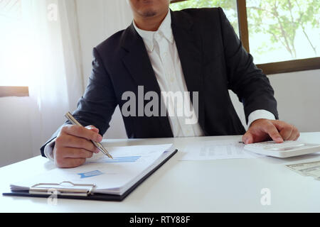 Businessman working in office using calculator with document on desk Stock Photo