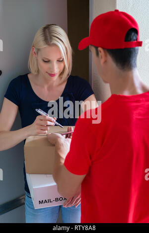 Woman signing on device to delivery parcel Stock Photo
