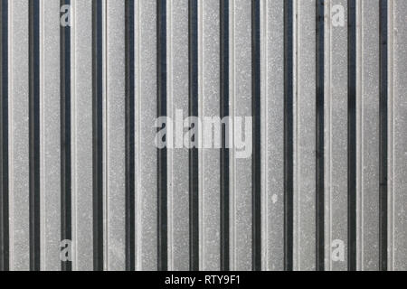 Metal plate fence, sun shining from side. Abstract construction background. Stock Photo