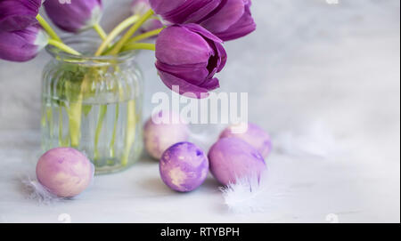 Spring Easter eggs and tulips flowers in a vase, Easter holiday card or greeting, painted purple eggs and tulips flowers Stock Photo