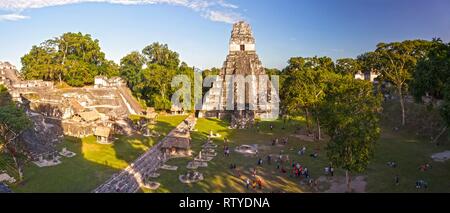 Panoramic Aerial View of Tourists and Grand Plaza Landscape surrounded by Ancient Mayan Citadels and Temple Ruins in Tikal National Park, Guatemala Stock Photo