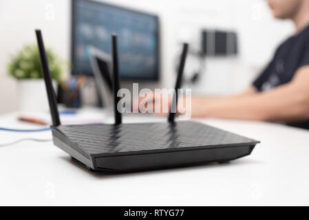 Modern dual band wireless router. Man working in the background. Fast and wireless internet concept. Stock Photo