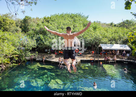 Man jumps off a cliff into the Cristalino cenote in Mexico. Stock Photo