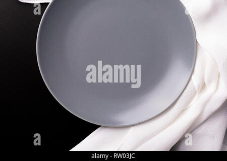 Dark wooden table, cutlery, gray plate and napkin on textured table top view. Table setting Stock Photo