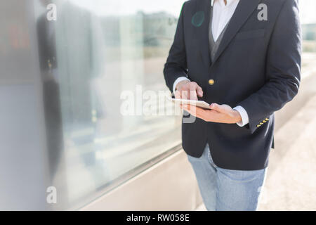 Young and Casual Businessman Using Tablet while Walking Outside of Office Building Stock Photo
