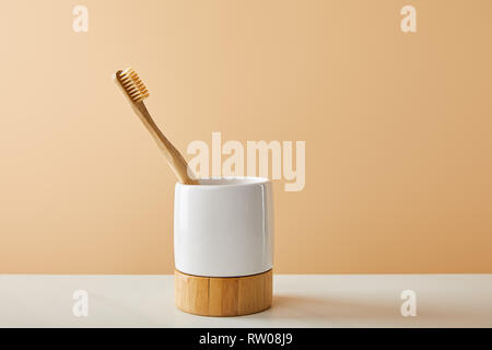 bamboo toothbrush in holder on white table and beige background Stock Photo