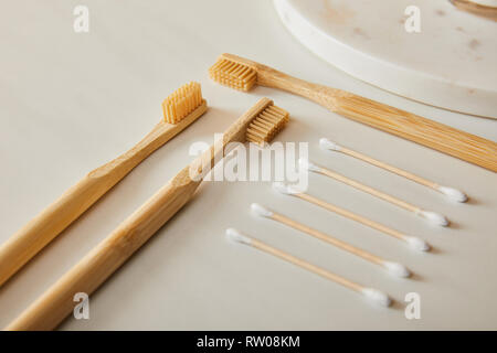 marble round board, bamboo toothbrushes and ear sticks on white background Stock Photo