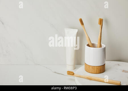 bamboo toothbrushes, holder and toothpaste in tube on white marble background Stock Photo