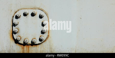Large nuts and bolts on gray steel plate of rail bridge, lit by bright sun. Abstract industrial background, space for text on the right. Stock Photo