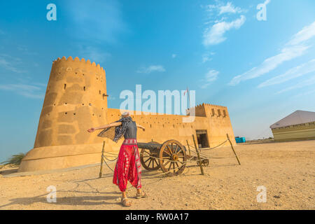Traveler in North of Qatar. Carefree woman at Al Zubara Fort, a historic Qatari military fortress, Middle East, Arabian Peninsula. Blonde tourist near