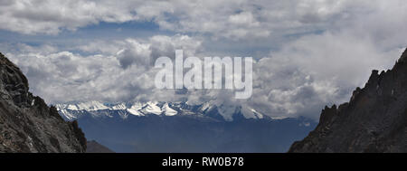 Mountain range with glaciers on top under powerful thunderstorm clouds, panorama. Stock Photo