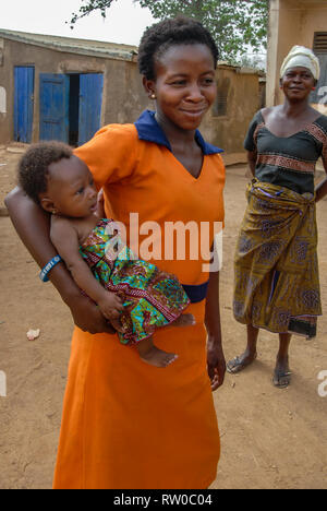 A photo of a young Ghanaian woman posing with her young baby boy dressed in a traditional Ghanaian fabric. Stock Photo