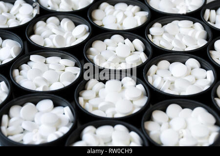 Group of white pills inside black circular aluminum cans Stock Photo