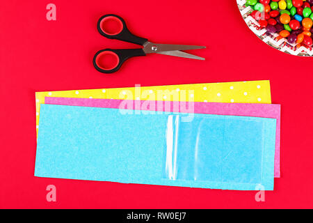 Diy Easter wrapping package sweets in a bag with a cut out bunny silhouette on a red background. Gift idea, decor Spring, Easter. Step by step. Top vi Stock Photo
