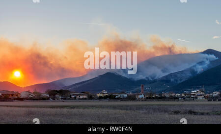 Panoramic view of the setting sun on a forest area burned by a large man-made fire, Monte Pisano, Tuscany, Italy Stock Photo