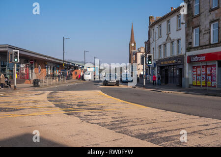 Largs, Scotland, UK - February 19, 2019: Busy Largs Town Centre on a unusually warm day for February 16-18°C with traffic flowing on the main street. Stock Photo