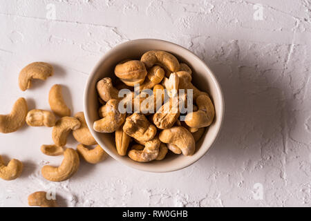 Cashew nuts in a bowl against white concrete background. Flat lay. Stock Photo