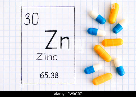 Handwriting chemical element Zinc Zn with pills. Close-up. Stock Photo