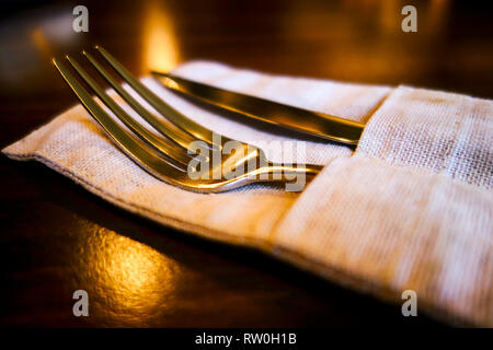 Fork and table knife in linen napkin on the table. Stock Photo