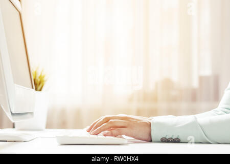 Woman working at office hand on keyboard close up. Sunlight in the window Stock Photo