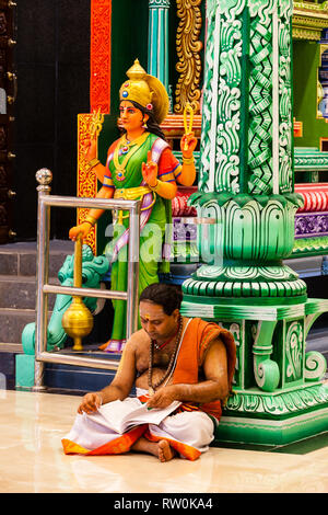 Batu Caves, Hindu Priest Reading in Temple at Base of Steps leading to Caves, Selangor, Malaysia. Stock Photo